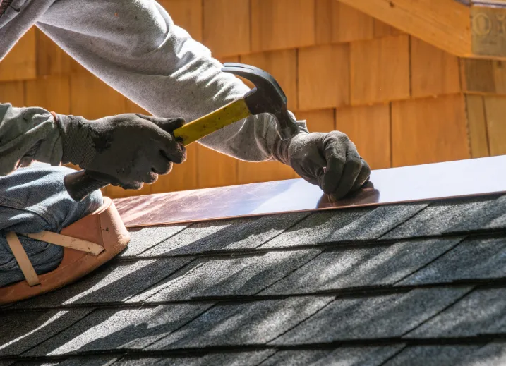 A roofing technician fixing loose shingles detected during winter roof inspections conducted by The Roofing Co
